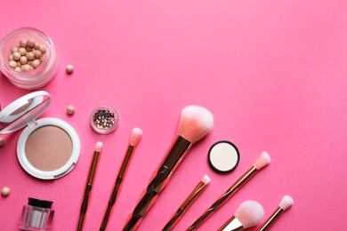 Flat lay composition with makeup brushes on pink background. Space for text