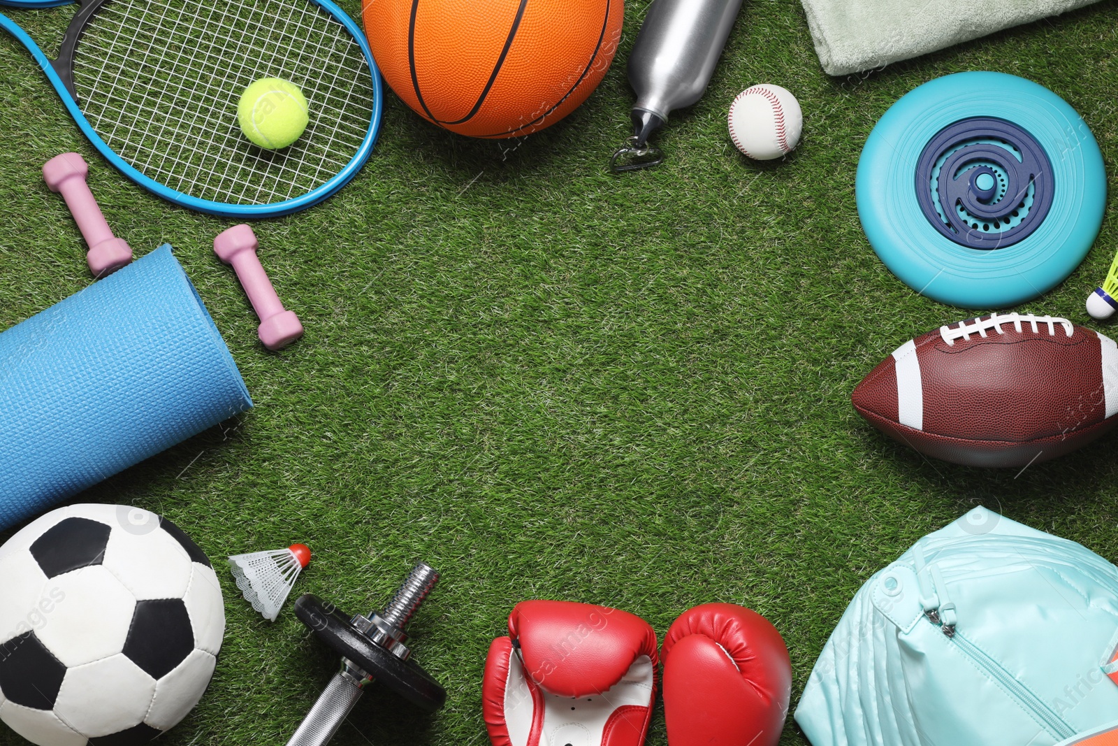 Photo of Frame of sports equipment on green grass, flat lay. Space for text