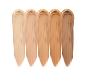 Different shades of liquid skin foundation on white background, top view