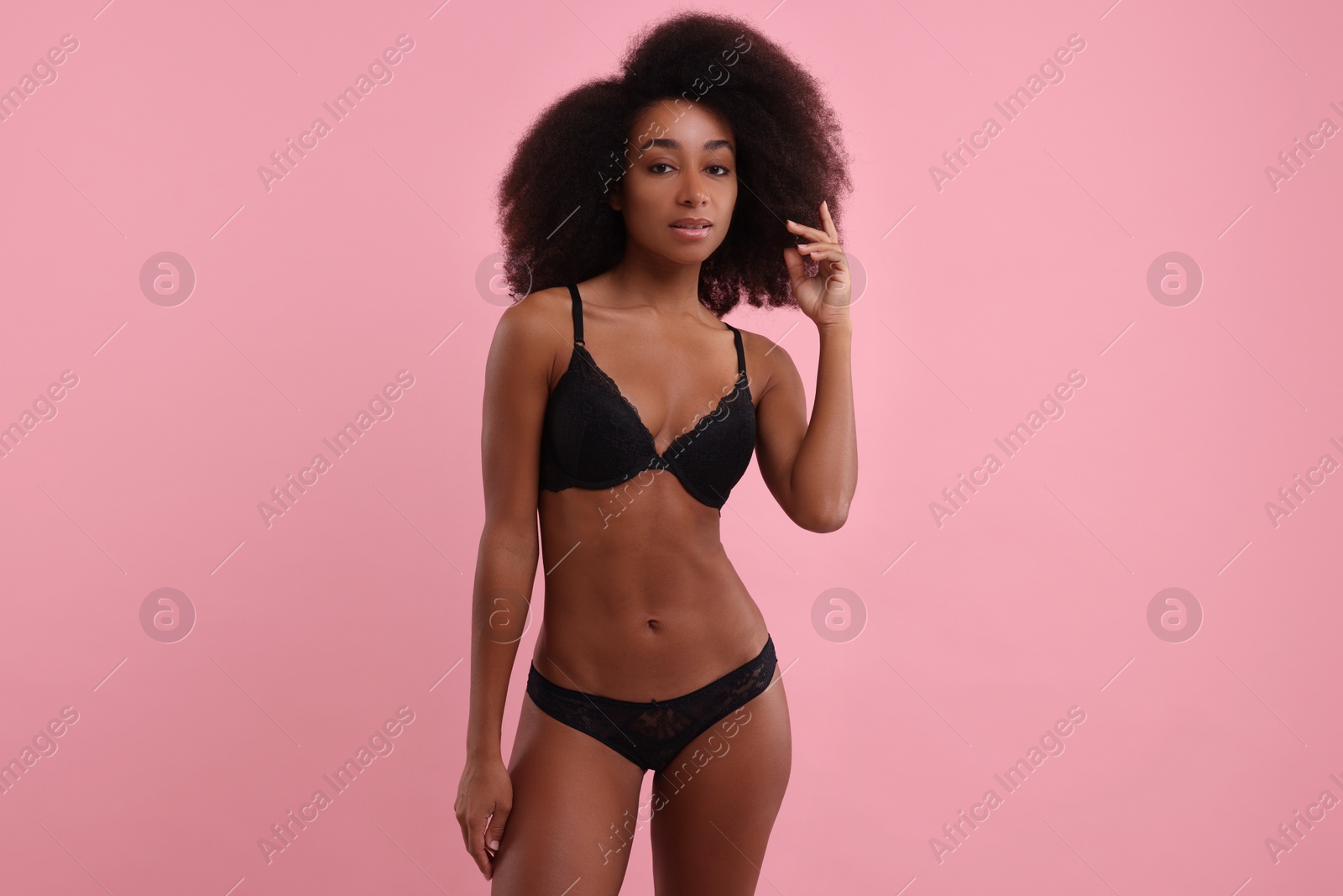 Photo of Beautiful woman in elegant black underwear on pink background