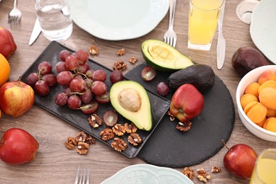 Healthy vegetarian food, glasses of juice, plates and cutlery on wooden table