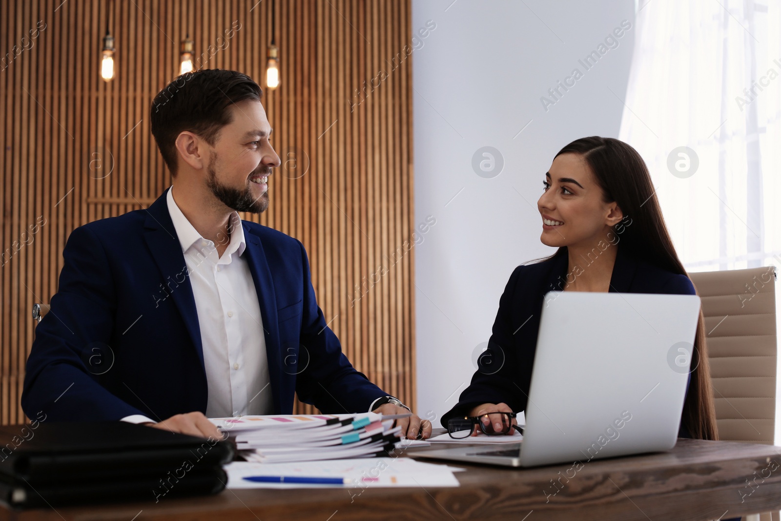 Photo of Office employees working with laptop and documents at table indoors