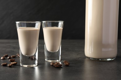 Photo of Coffee cream liqueur in glasses, bottle and beans on grey table