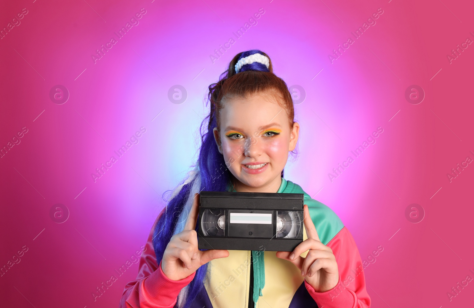 Photo of Cute indie girl with VHS cassette on violet background