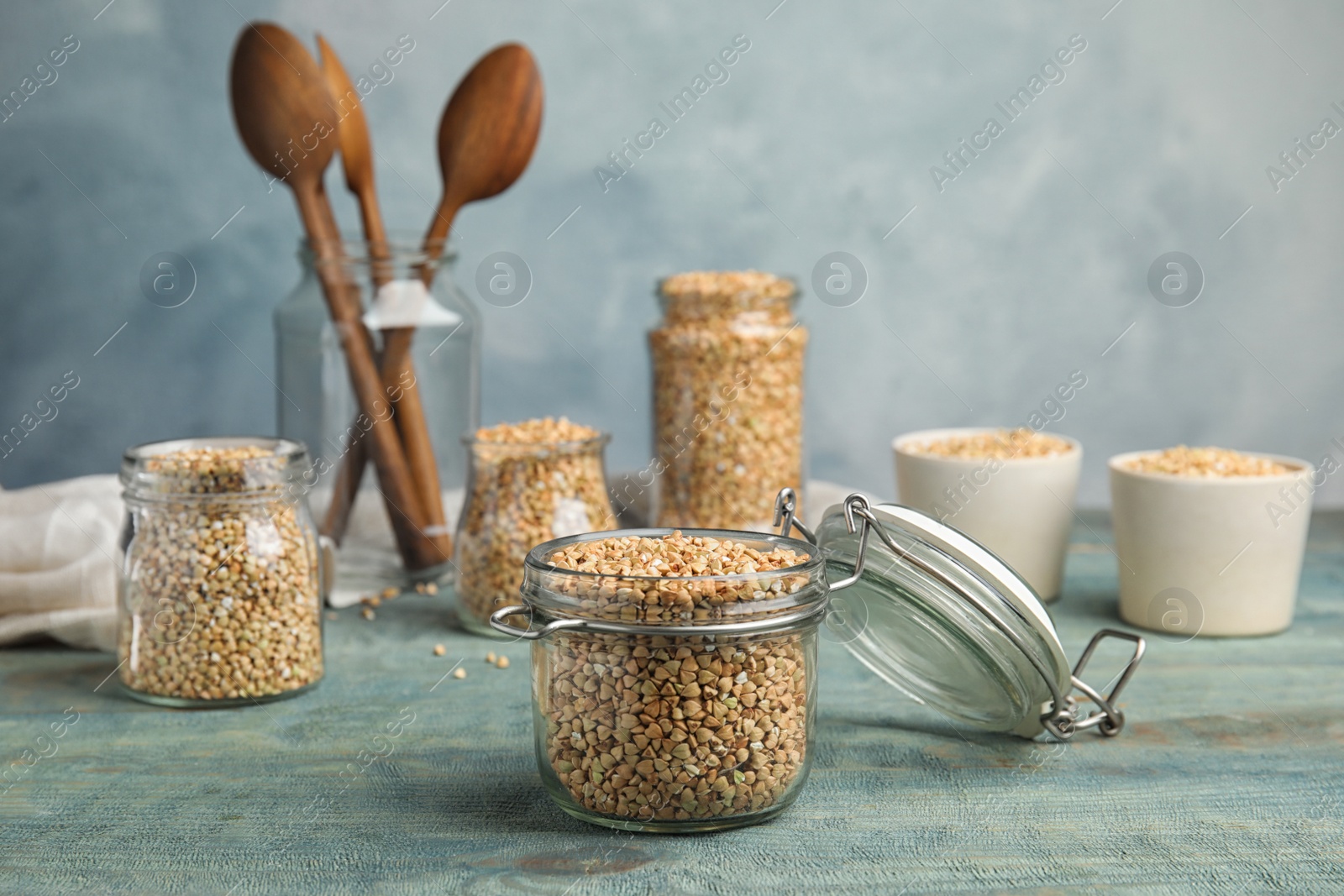 Photo of Uncooked green buckwheat grains on light blue wooden table