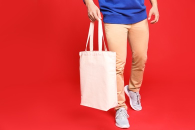 Photo of Young man with eco bag on red background, closeup