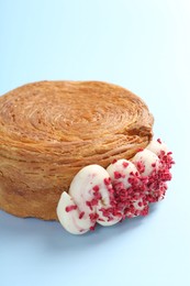 Photo of One supreme croissant with cream on light blue background, closeup. Tasty puff pastry