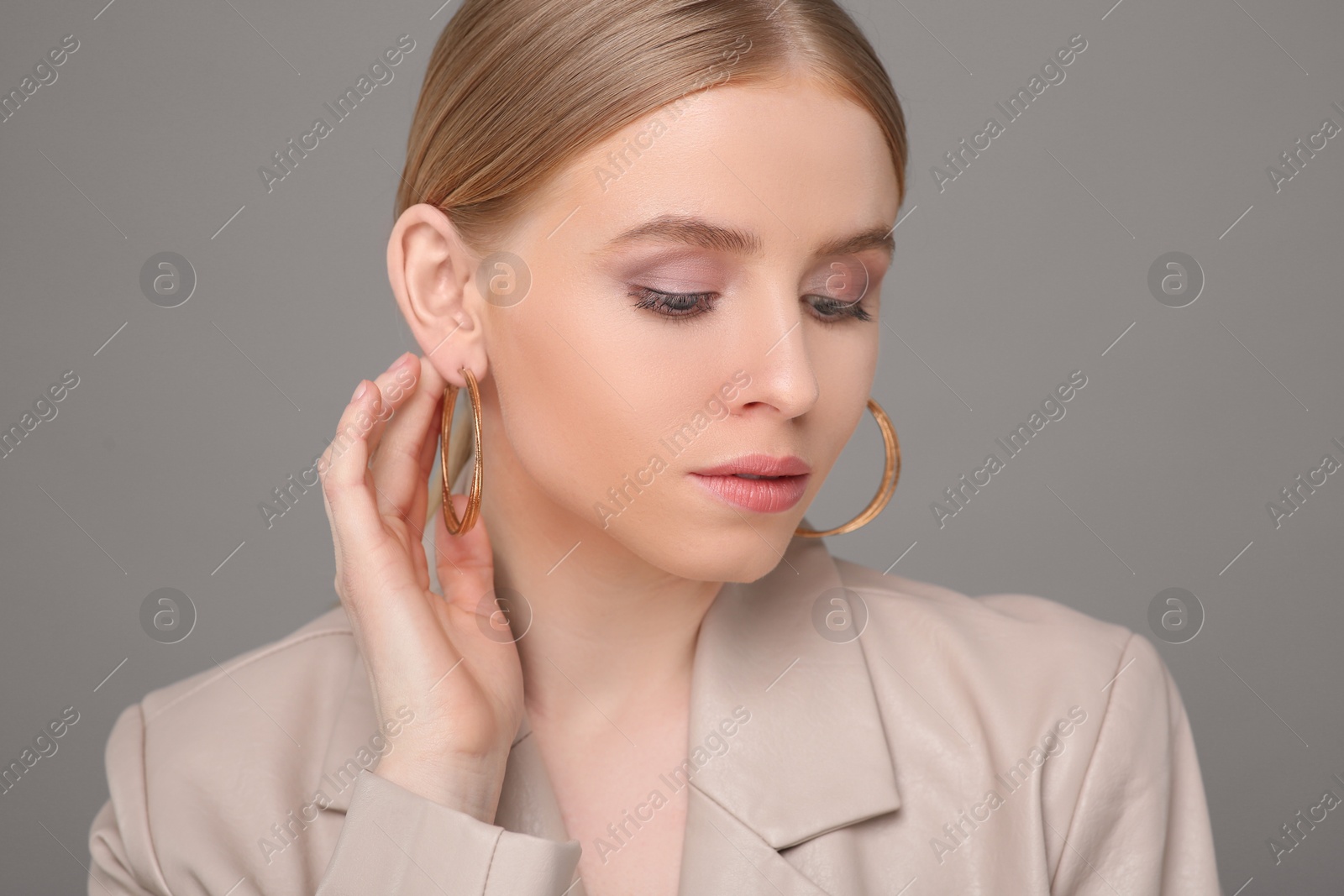 Photo of Beautiful young woman with elegant earrings on gray background