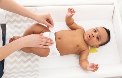 Mother changing her baby's diaper on table, above view