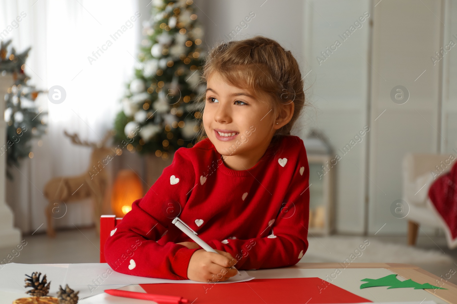 Photo of Cute child writing letter to Santa Claus at table indoors. Christmas tradition