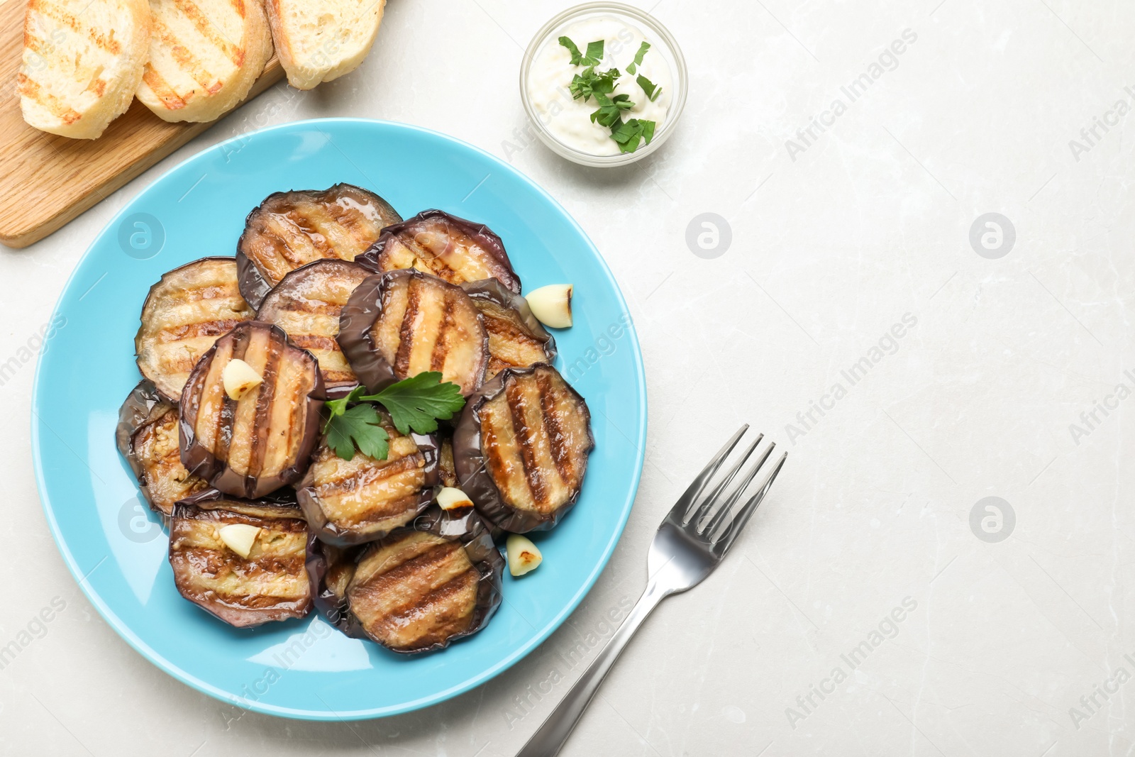 Photo of Delicious grilled eggplant slices on light table, flat lay. Space for text