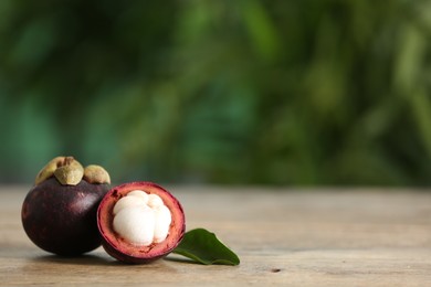 Photo of Delicious tropical mangosteen fruits on wooden table. Space for text