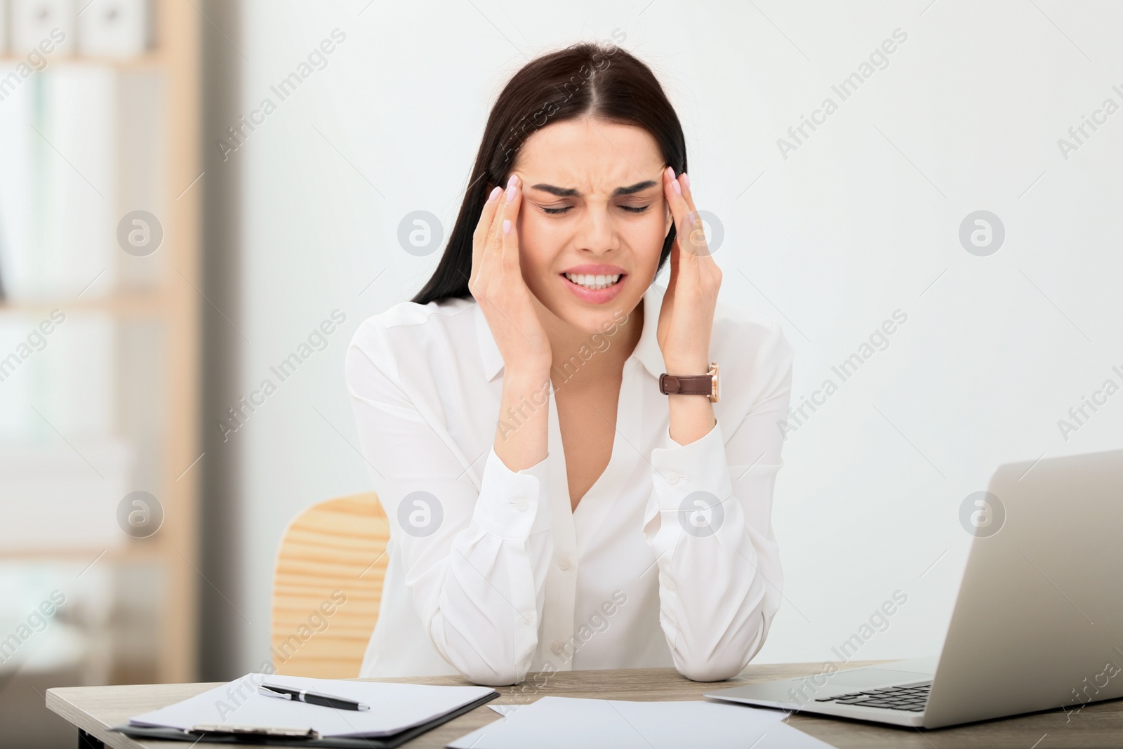 Photo of Woman suffering from migraine at workplace in office