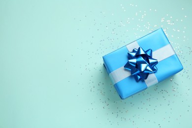 Photo of Gift box and confetti on light blue background, flat lay. Space for text