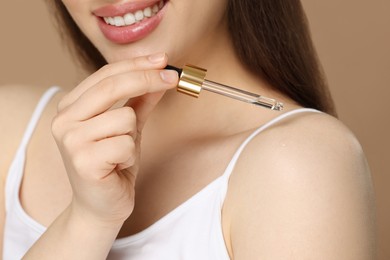 Photo of Happy woman applying essential oil onto shoulder on brown background, closeup