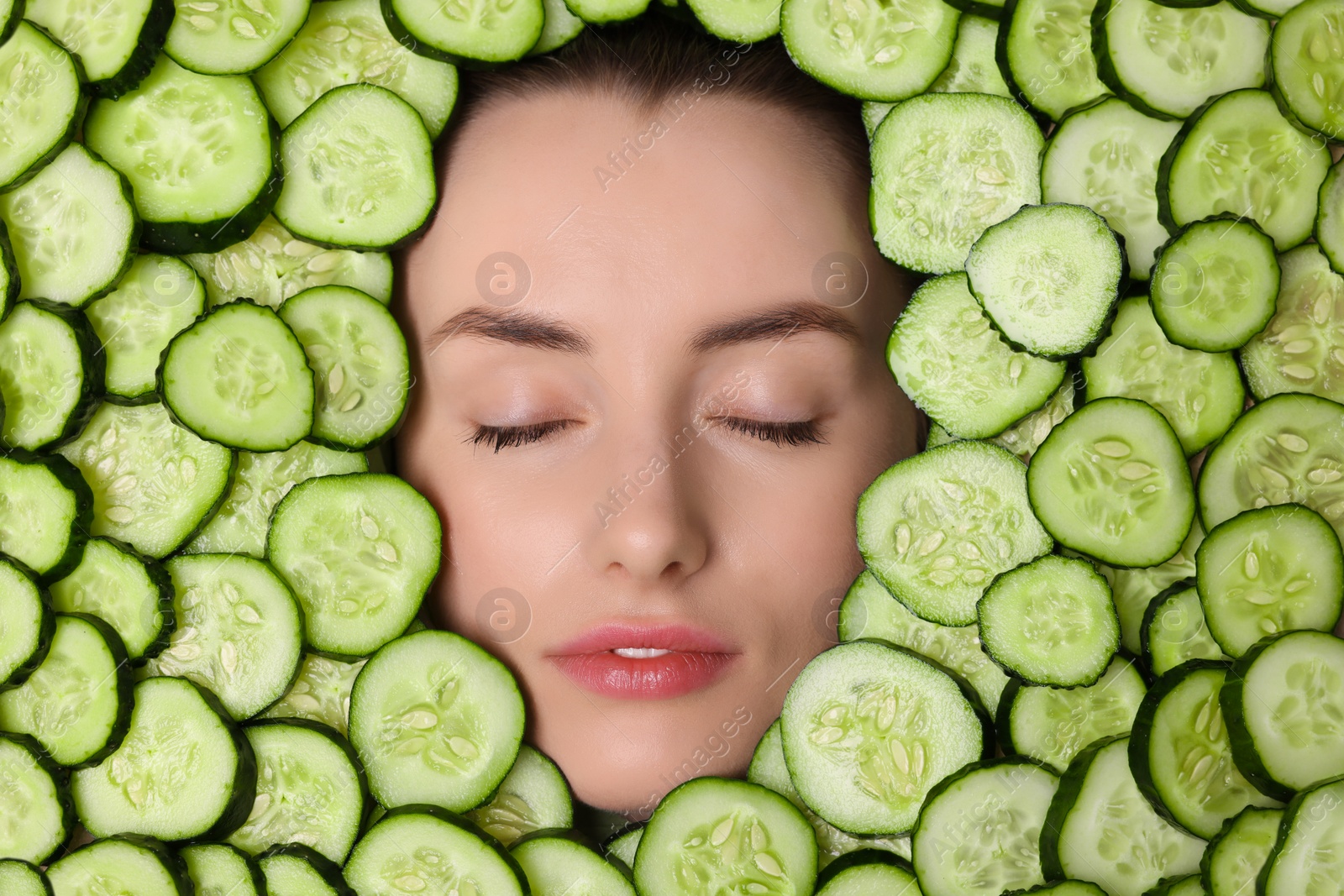 Photo of Beautiful woman among cucumber slices, top view