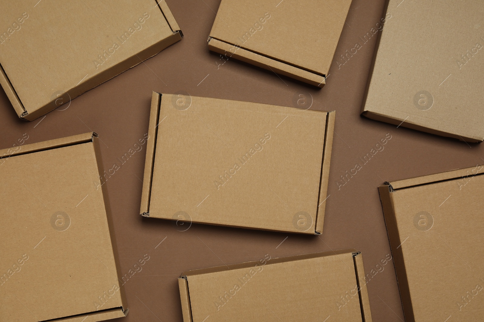 Photo of Many closed cardboard boxes on brown background, flat lay