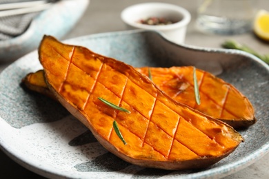 Plate with baked sweet potato slices on table, closeup