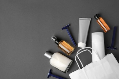 Different men's shaving accessories and paper bag on dark grey background, flat lay. Space for text