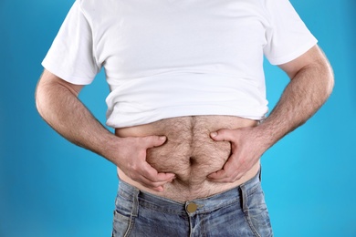 Overweight man with large belly on color background, closeup