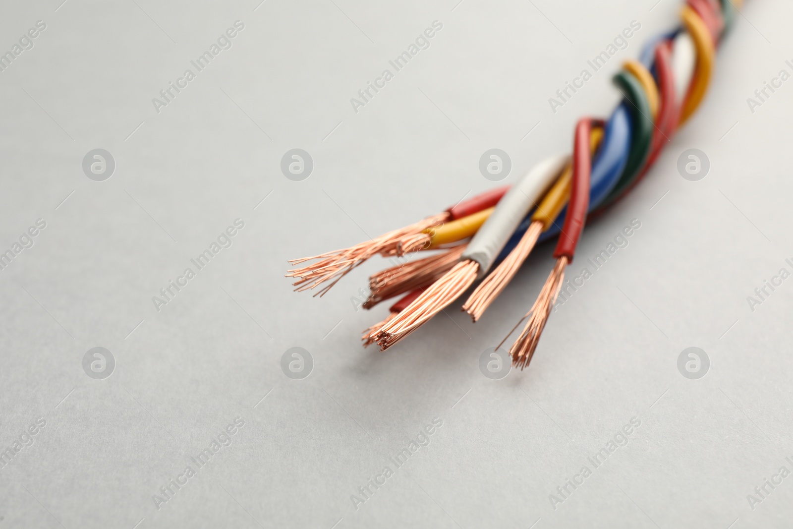 Photo of Many twisted electrical wires on light background, closeup