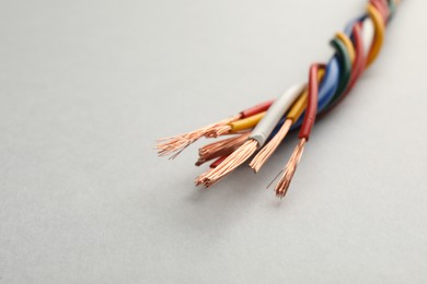 Many twisted electrical wires on light background, closeup