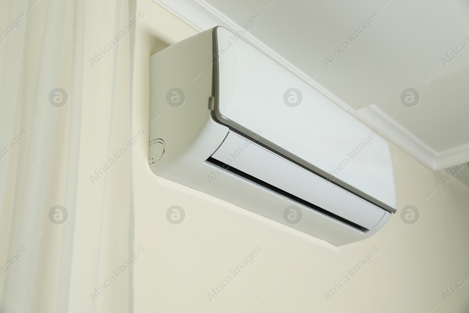 Photo of Modern air conditioner on white wall indoors