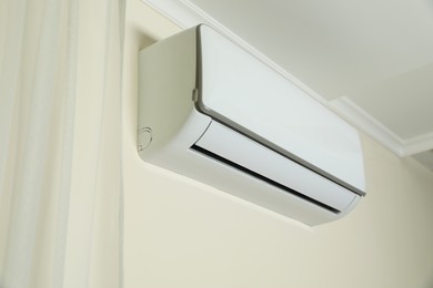 Modern air conditioner on white wall indoors