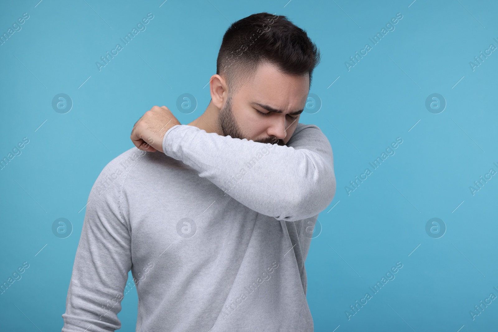 Photo of Sick man coughing on light blue background