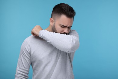 Photo of Sick man coughing on light blue background