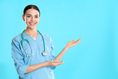 Photo of Portrait of young doctor with stethoscope on blue background. Space for text