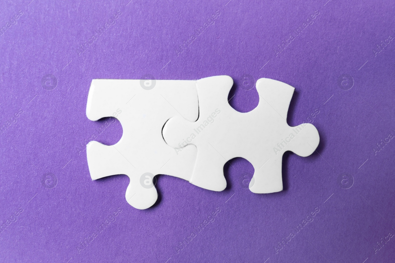 Photo of Unfitting white puzzle pieces on purple background, flat lay