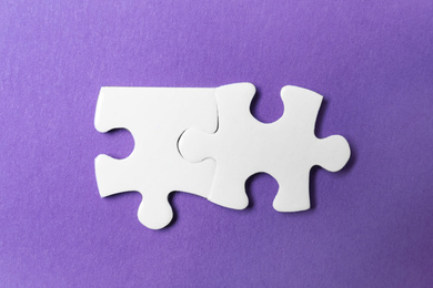 Unfitting white puzzle pieces on purple background, flat lay