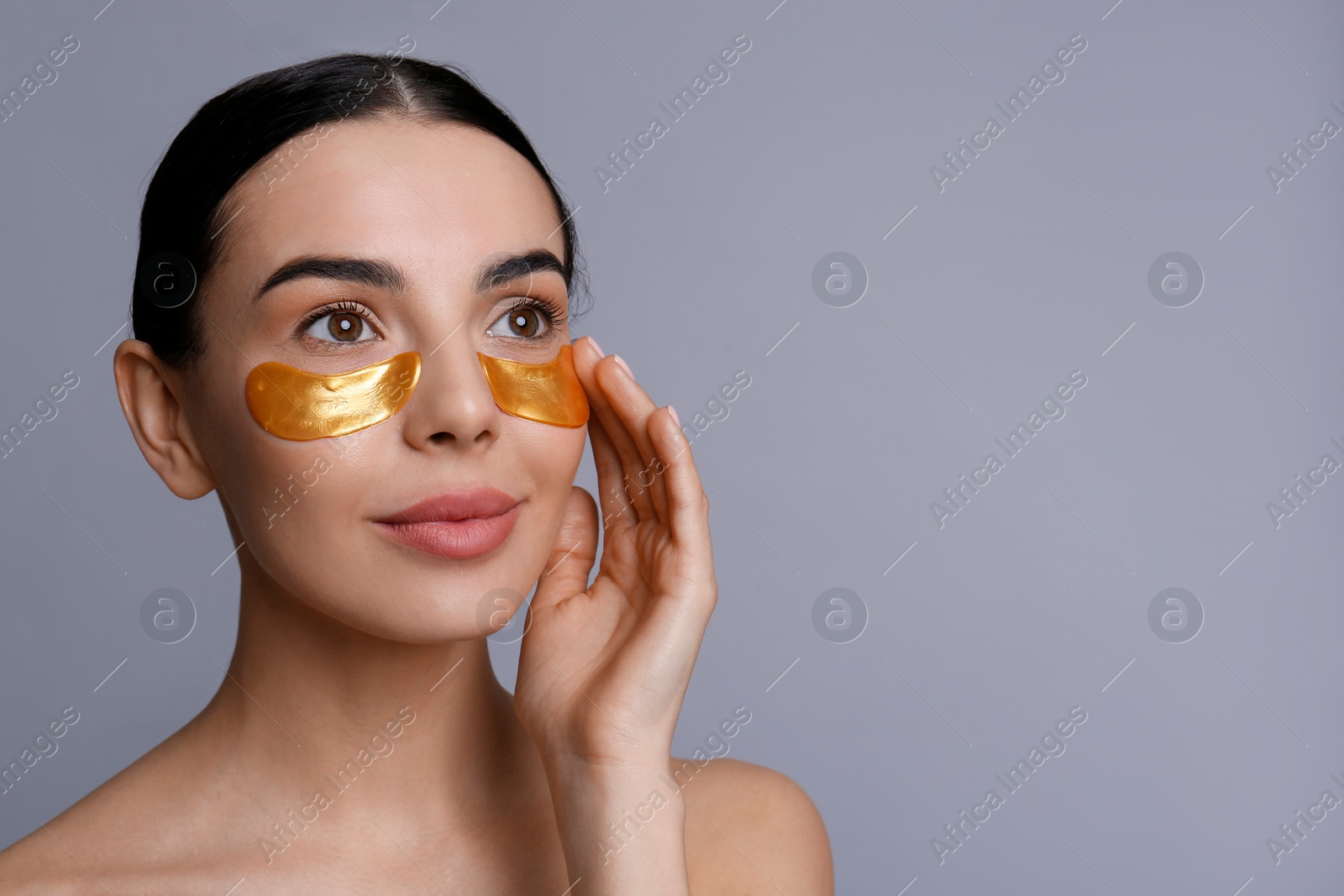 Photo of Beautiful young woman with under eye patches on grey background, space for text