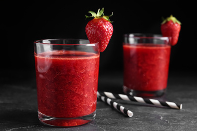 Photo of Tasty strawberry smoothie in glass on black table