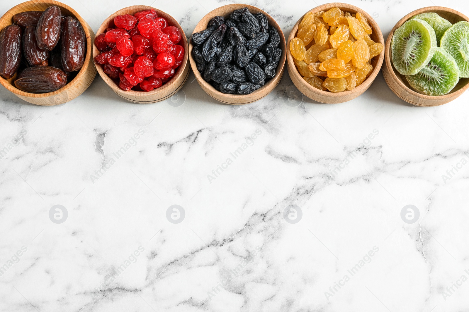 Photo of Bowls of different dried fruits on marble background, top view with space for text. Healthy lifestyle