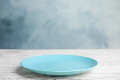 Photo of Empty light blue plate on white wooden table