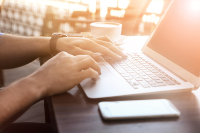 Man working with laptop at table in outdoor cafe, closeup