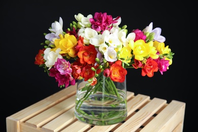 Bouquet of spring freesia flowers in vase on dark background