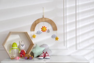 Photo of Different baby accessories and toys on white table in child room. Interior design