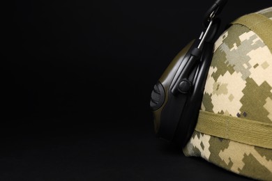 Photo of Helmet and tactical headphone on black background, closeup with space for text. Military training equipment