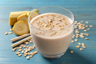 Photo of Glass of tasty banana smoothie with oatmeal on light blue wooden table