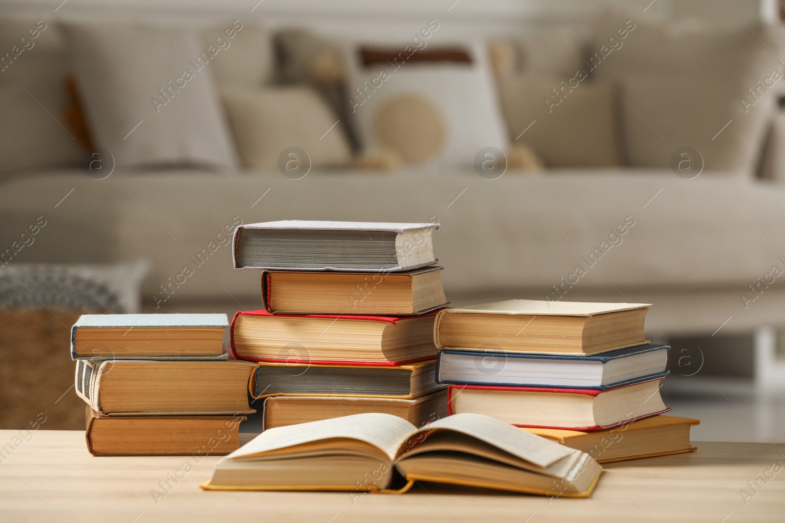 Photo of Many books on wooden table in living room. Home library