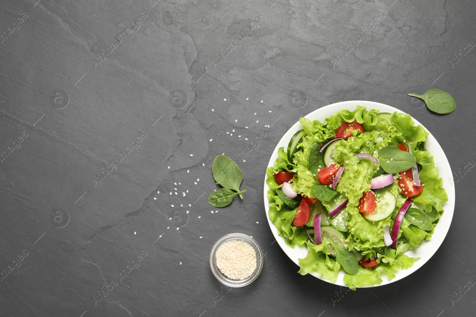 Photo of Delicious salad in bowl on grey table, flat lay. Space for text