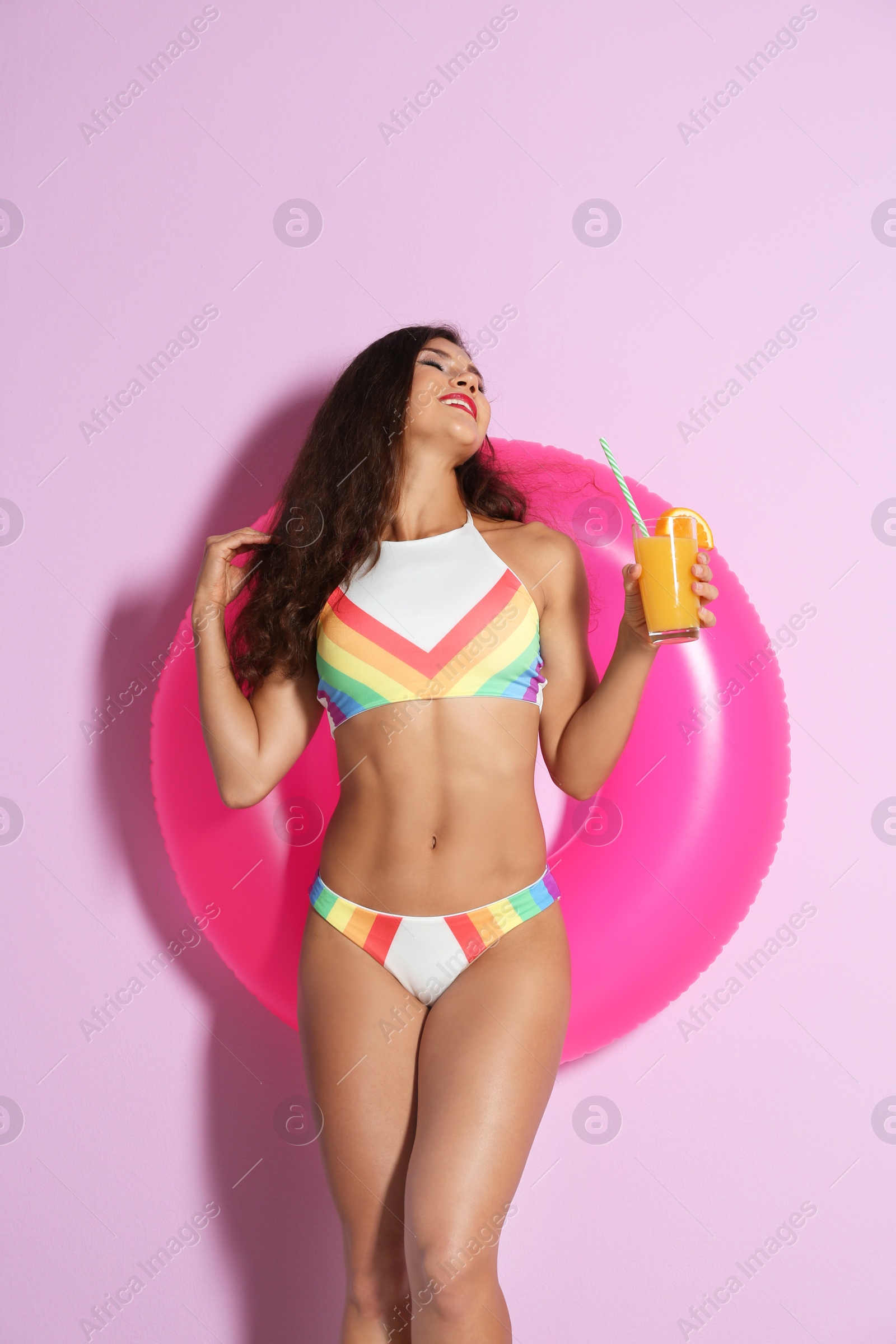 Photo of Beautiful young woman with inflatable ring and glass of cocktail on color background