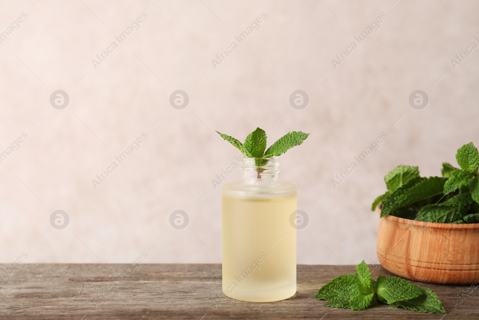 Photo of Glass bottle with essential oil and mint on wooden table