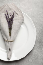 Plate with fabric napkin, decorative ring and lavender on gray background, top view