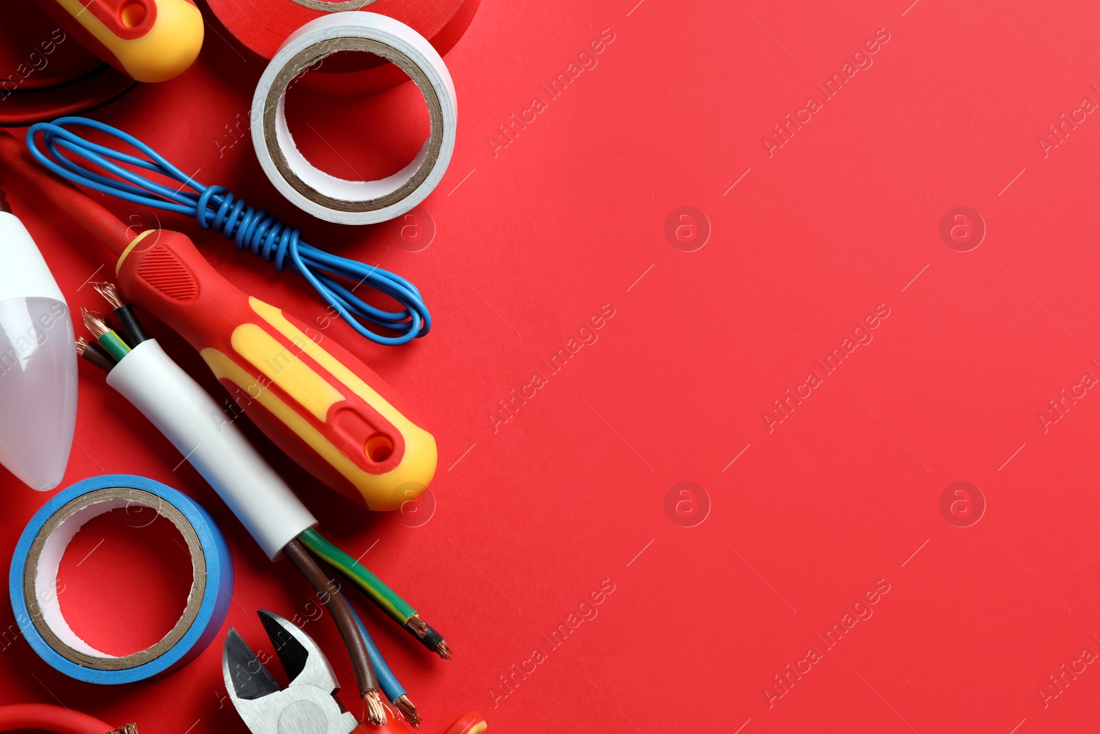 Photo of Set of electrician's tools and accessories on red background, flat lay. Space for text