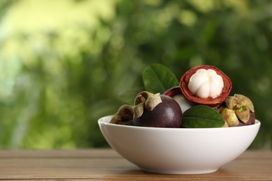 Photo of Delicious ripe mangosteen fruits on wooden table outdoors, space for text