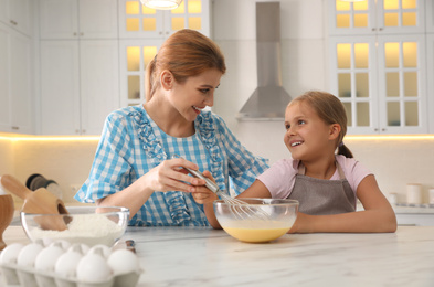 Mother and daughter making dough together in kitchen